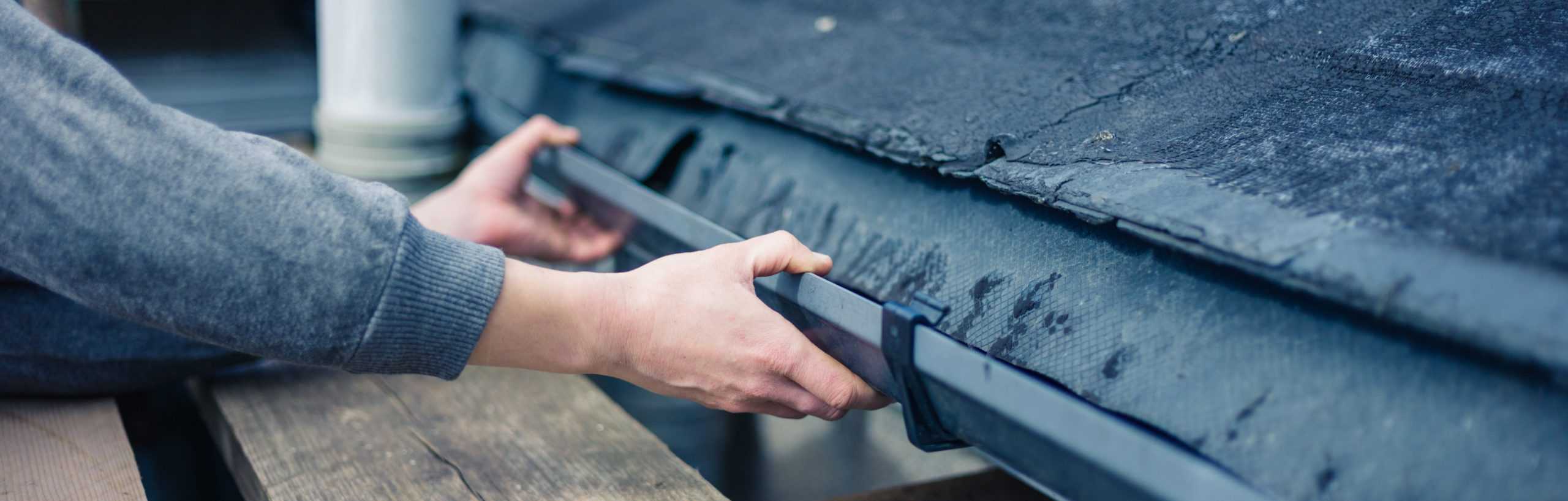 Hand of worker inspecting drain and roof